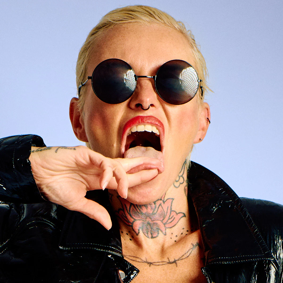 Lu Epic nude in a black latex coat and blue boots, posed in a minimalist art portrait