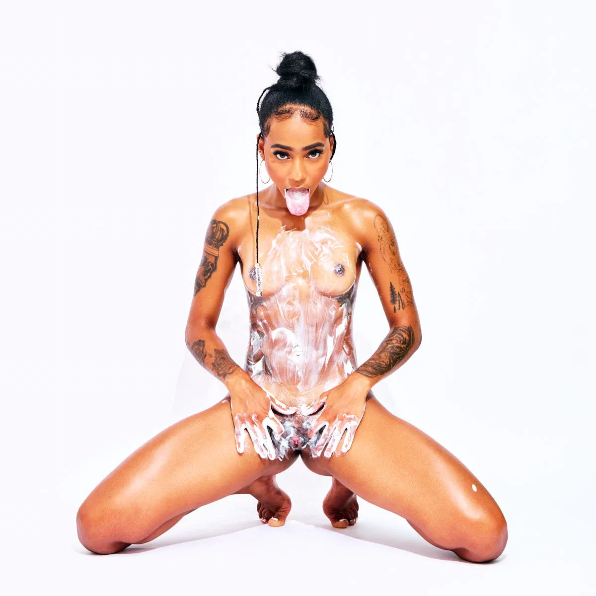 Tattooed Cape Verdean model African Beauty nude applying cream on her body