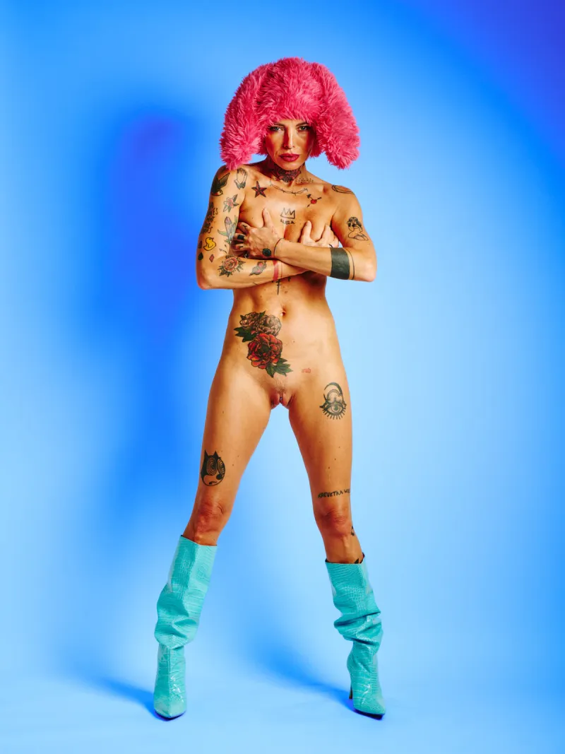 Tattooed nude model in the Red Rabbit series wearing red fur hat with rabbit ears
